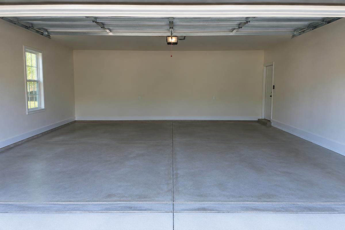 The same garage completely empty with a swept concrete floor after junk removal