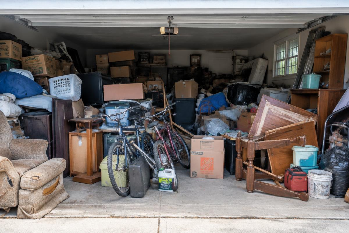 Cluttered two-car garage packed with boxes and old furniture before junk removal